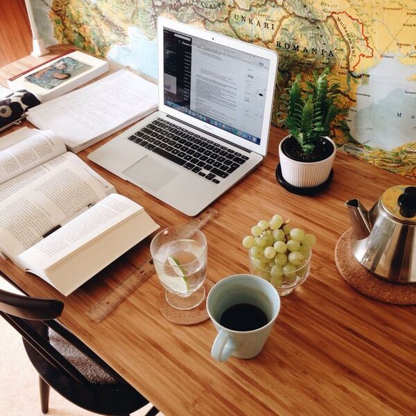 ڈیسک پر پودے، نوٹ بک اور چائے کے کپ کے ساتھ پرسکون ورک اسپیس